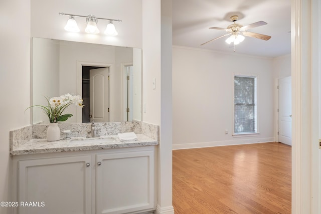 bathroom with vanity, wood-type flooring, ornamental molding, and ceiling fan