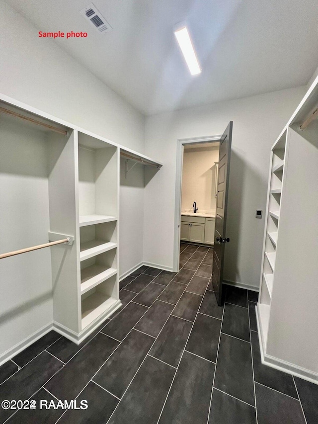 spacious closet with a sink, visible vents, and dark tile patterned floors