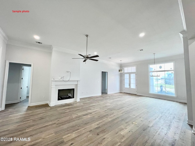 unfurnished living room with baseboards, ceiling fan, ornamental molding, light wood-style flooring, and a fireplace