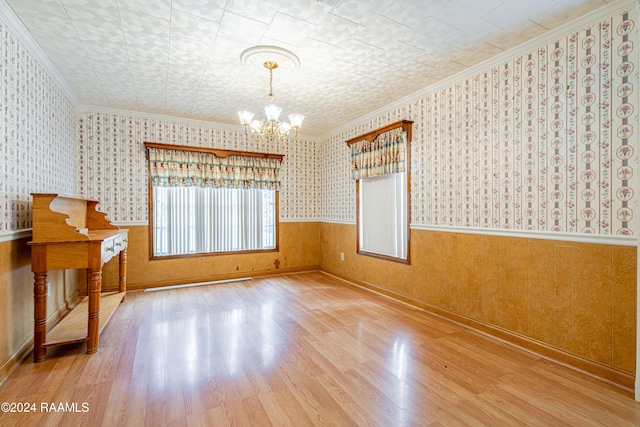 spare room featuring a chandelier, crown molding, and wood-type flooring