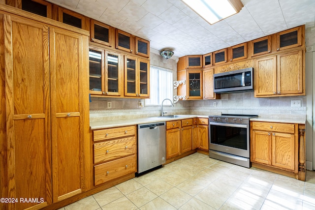 kitchen with decorative backsplash, sink, light tile patterned floors, and stainless steel appliances