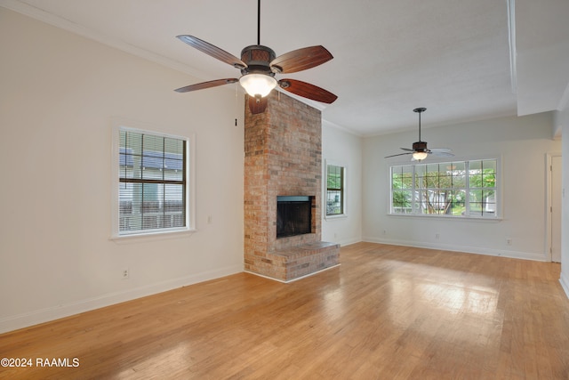 unfurnished living room featuring a brick fireplace, ceiling fan, light wood-type flooring, and crown molding