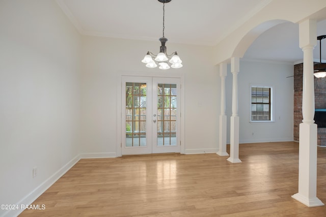 unfurnished dining area with a chandelier, light hardwood / wood-style flooring, french doors, and ornamental molding