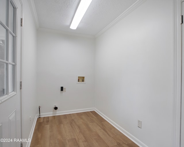 clothes washing area with washer hookup, a textured ceiling, light hardwood / wood-style floors, and crown molding