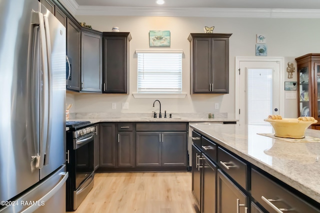 kitchen featuring sink, stainless steel appliances, light stone counters, light hardwood / wood-style floors, and ornamental molding