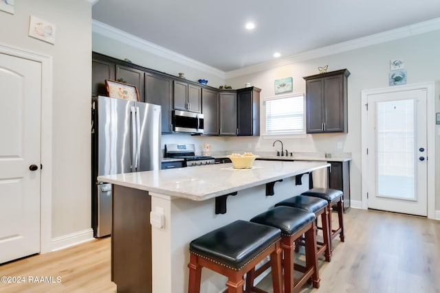 kitchen featuring a kitchen bar, a center island, light wood-type flooring, and appliances with stainless steel finishes