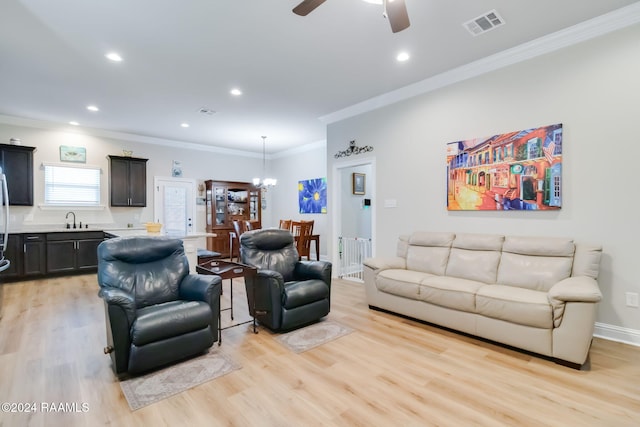 living room with ceiling fan with notable chandelier, light hardwood / wood-style flooring, ornamental molding, and sink