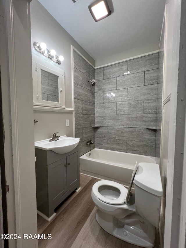 full bathroom with toilet, tiled shower / bath combo, vanity, and hardwood / wood-style floors