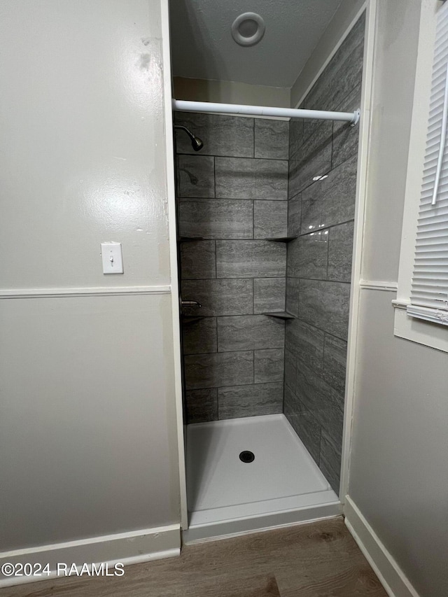 bathroom featuring hardwood / wood-style floors and a tile shower