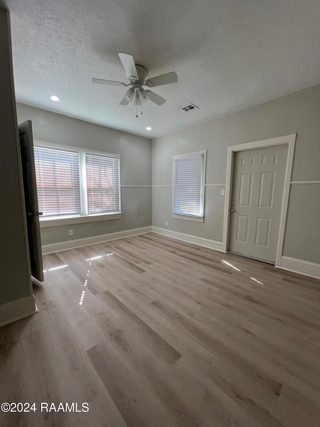 interior space featuring light wood-type flooring, a textured ceiling, and ceiling fan