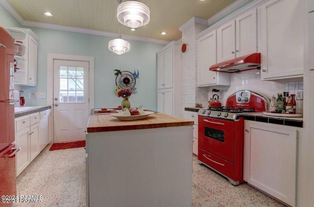 1015 Lee Ave, Lafayette, LA 70501 - kitchen with under cabinet range hood, gas stove, dark speckled floor, wooden counters, and a center island