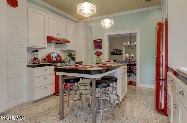 1015 Lee Ave, Lafayette, LA 70501 - kitchen with dark aggregate flooring, tile countertops, under cabinet range hood, white cabinets, and ornamental molding