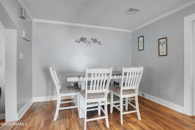 dining area featuring hardwood / wood-style floors and crown molding