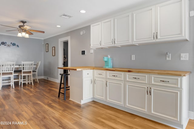 kitchen featuring white cabinetry, light hardwood / wood-style floors, a breakfast bar area, and ceiling fan