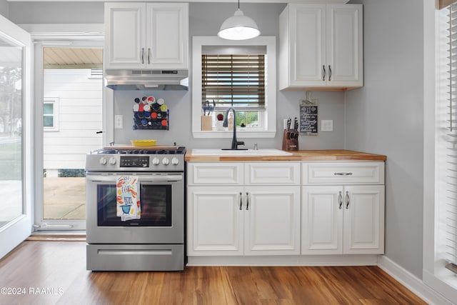 kitchen with white cabinetry, extractor fan, pendant lighting, light hardwood / wood-style floors, and stainless steel range oven