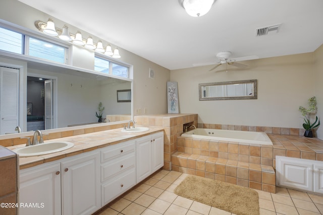 bathroom featuring tile patterned flooring, vanity, ceiling fan, and a relaxing tiled tub