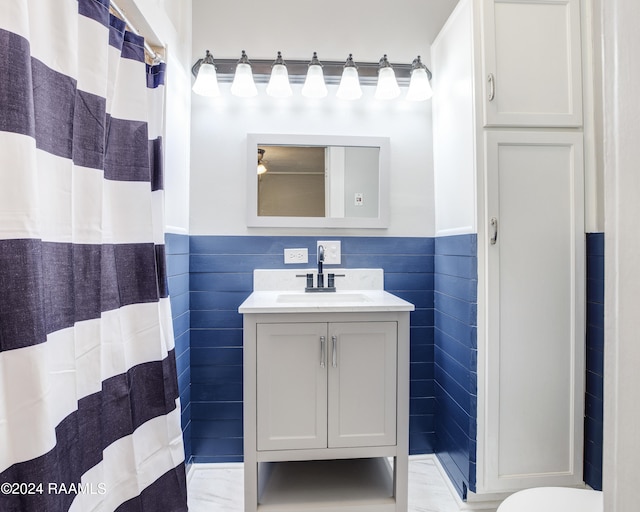 bathroom with walk in shower, vanity, and tile walls