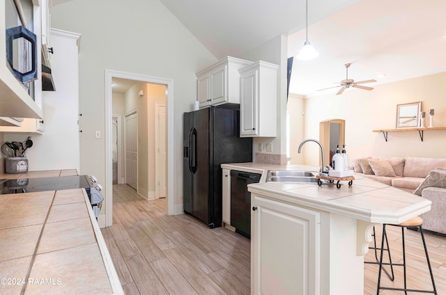 kitchen with tile countertops, white cabinets, black appliances, sink, and pendant lighting