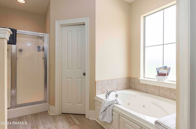 bathroom with a wealth of natural light, hardwood / wood-style flooring, and separate shower and tub