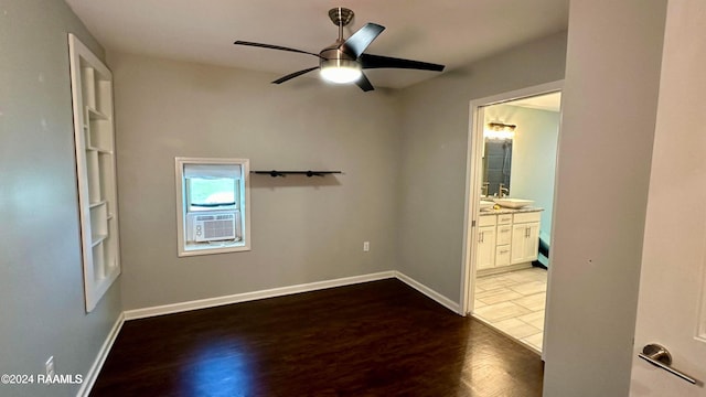 empty room featuring light hardwood / wood-style floors, ceiling fan, cooling unit, and sink