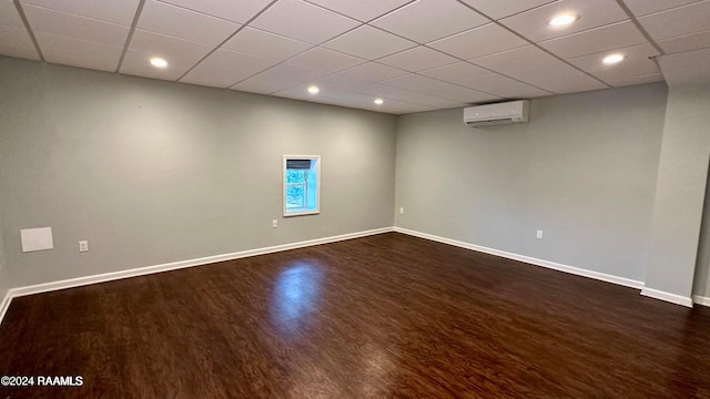 unfurnished room featuring dark wood-type flooring, a paneled ceiling, and a wall mounted AC