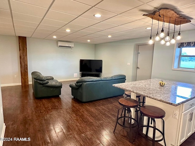 living room featuring dark wood-type flooring, an AC wall unit, and a drop ceiling