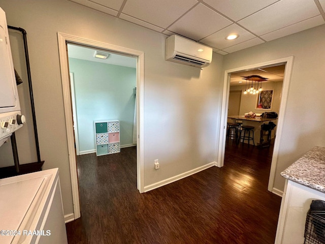 corridor with a wall mounted AC, dark hardwood / wood-style flooring, and a drop ceiling