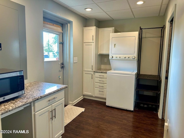 laundry room featuring stacked washing maching and dryer and dark hardwood / wood-style floors