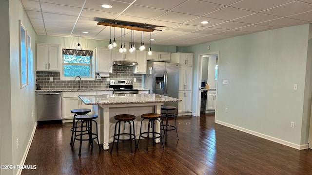 kitchen featuring appliances with stainless steel finishes, light stone counters, dark hardwood / wood-style floors, and a center island