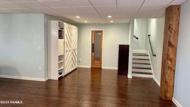 interior space featuring dark hardwood / wood-style flooring and a drop ceiling