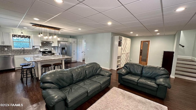 living room with dark hardwood / wood-style floors, a paneled ceiling, and sink