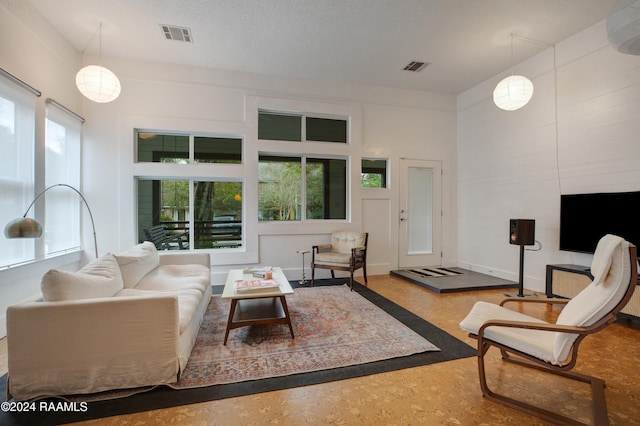 living room with plenty of natural light, an AC wall unit, a textured ceiling, and a high ceiling