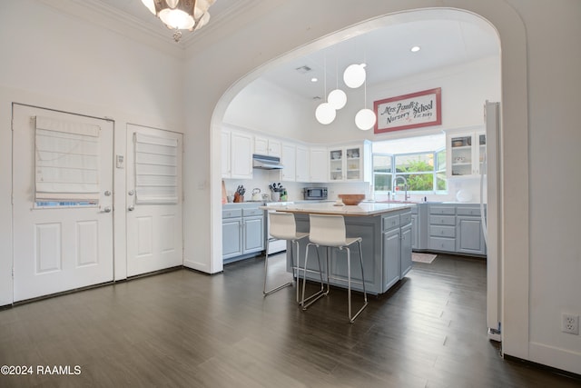 kitchen with white cabinetry, ornamental molding, hanging light fixtures, and a kitchen island