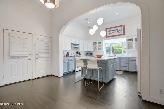 228 Cherry St, Lafayette, LA 70506 - kitchen with ornamental molding, under cabinet range hood, arched walkways, glass insert cabinets, and a center island