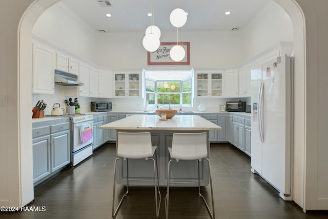 kitchen featuring white cabinetry, hanging light fixtures, white appliances, and a center island