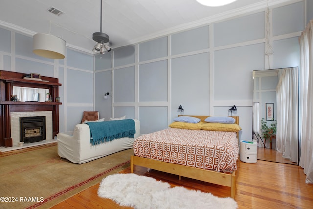 bedroom with ornamental molding, hardwood / wood-style floors, and a brick fireplace