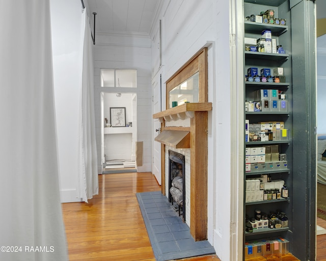 hallway with crown molding, wooden walls, and hardwood / wood-style floors