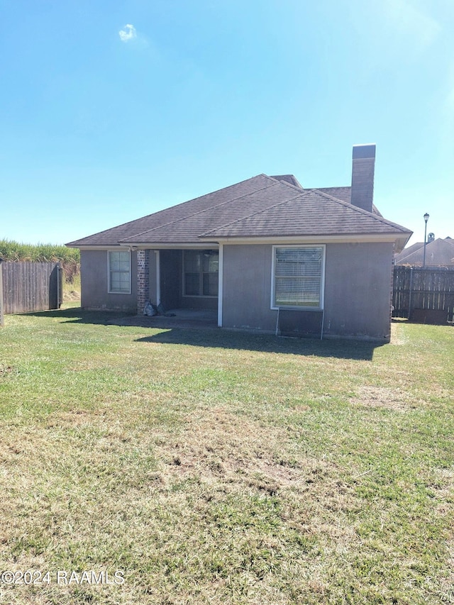 rear view of property featuring a lawn