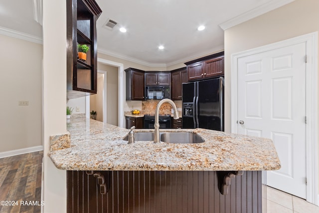 kitchen with kitchen peninsula, ornamental molding, black appliances, and light wood-type flooring