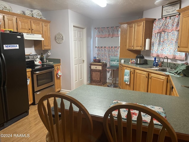 kitchen with light hardwood / wood-style floors, sink, a textured ceiling, black refrigerator, and electric range