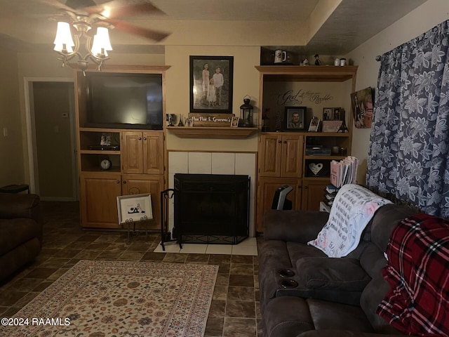 living room featuring ceiling fan and a tiled fireplace