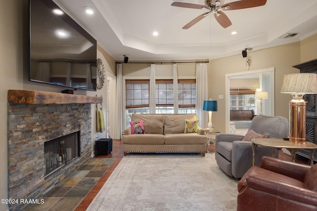 living room featuring a fireplace, ceiling fan, a raised ceiling, and ornamental molding