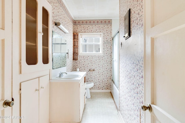 full bathroom featuring toilet, combined bath / shower with glass door, vanity, and ornamental molding