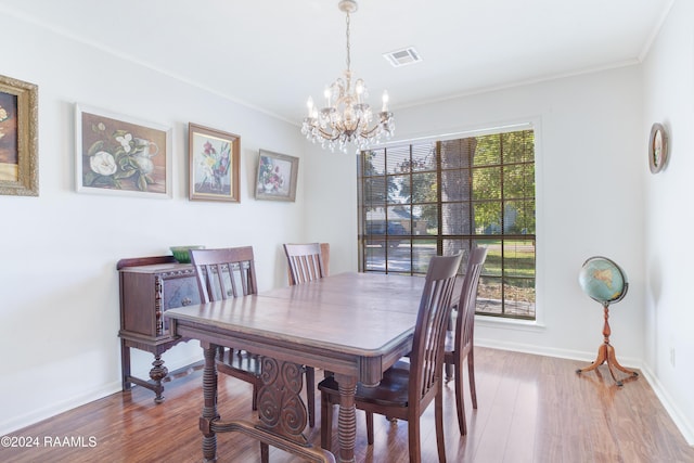 dining space featuring hardwood / wood-style flooring, crown molding, and an inviting chandelier