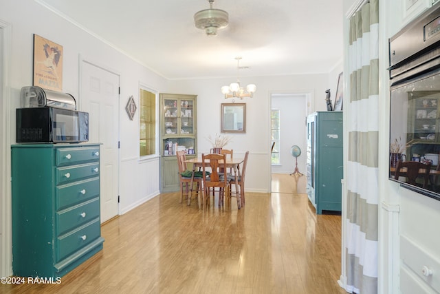 dining room with light hardwood / wood-style flooring, a notable chandelier, and crown molding