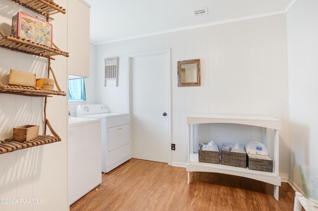 laundry room with crown molding, washer and clothes dryer, and light hardwood / wood-style floors