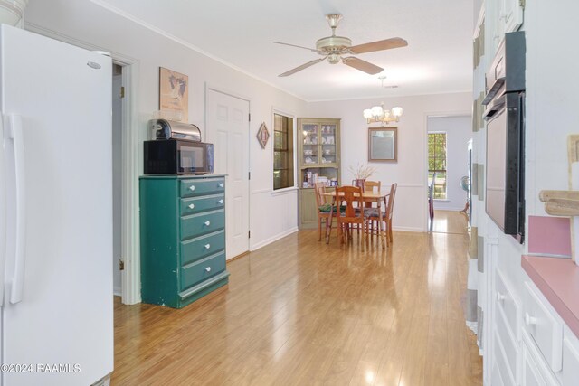 dining area featuring ornamental molding, ceiling fan with notable chandelier, and light wood-type flooring