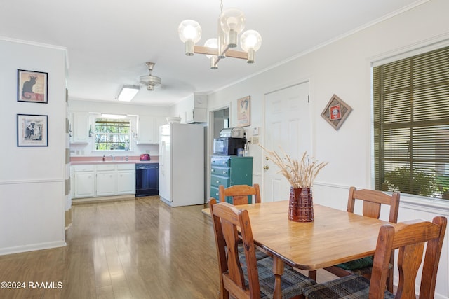 dining room featuring crown molding, light hardwood / wood-style flooring, ceiling fan with notable chandelier, and sink