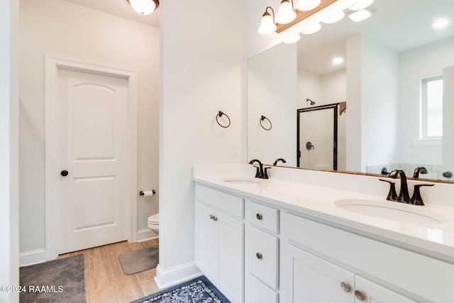 bathroom featuring hardwood / wood-style floors, vanity, toilet, and a shower with shower door