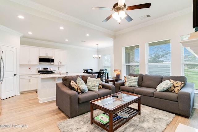 living room featuring a healthy amount of sunlight, light wood-type flooring, and ornamental molding